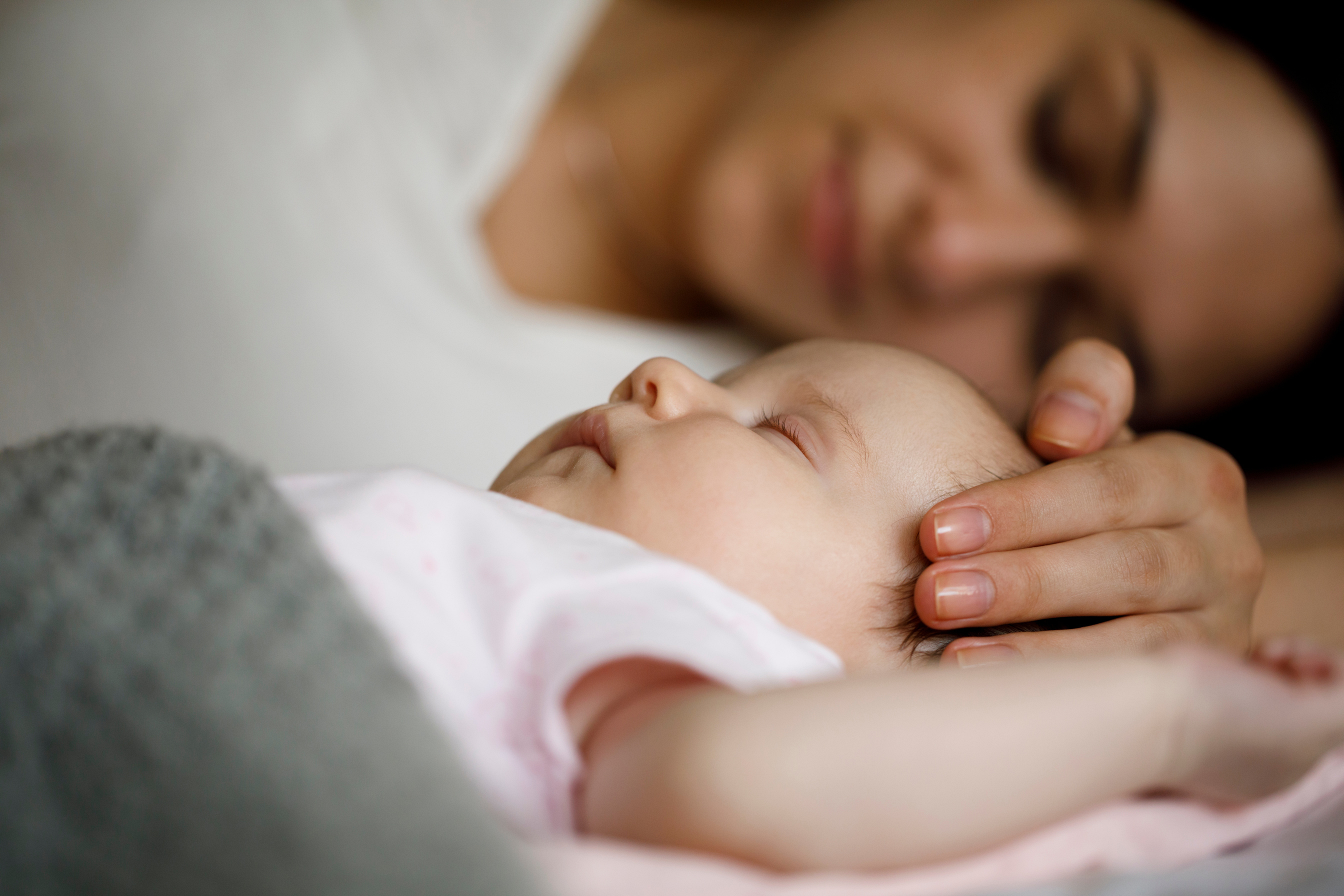 Mother and baby sleeping together at home